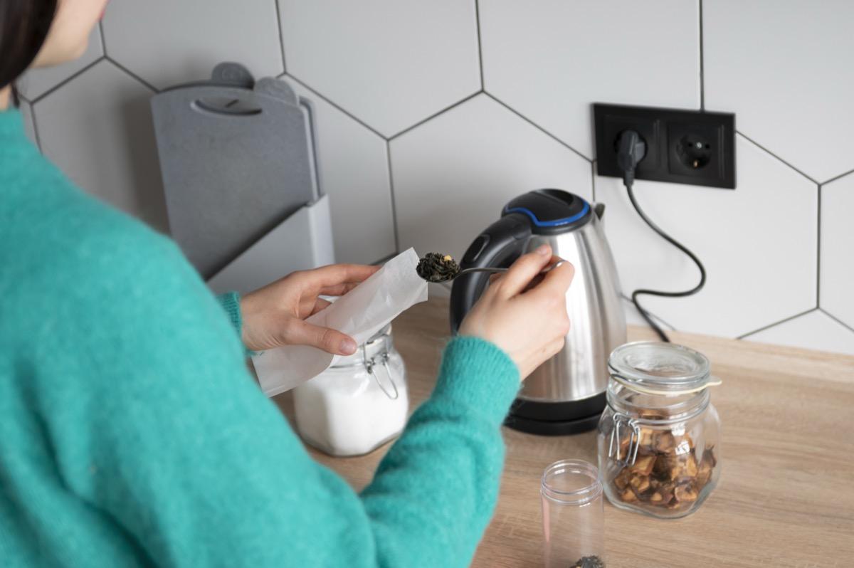 Kobieta i czajnik elektryczny do gniazdka w kuchni