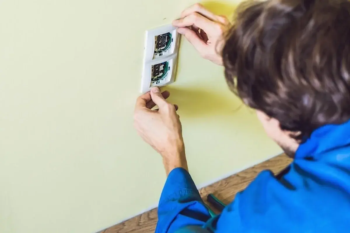 Elektryk instaluje gniazdko w ścianie