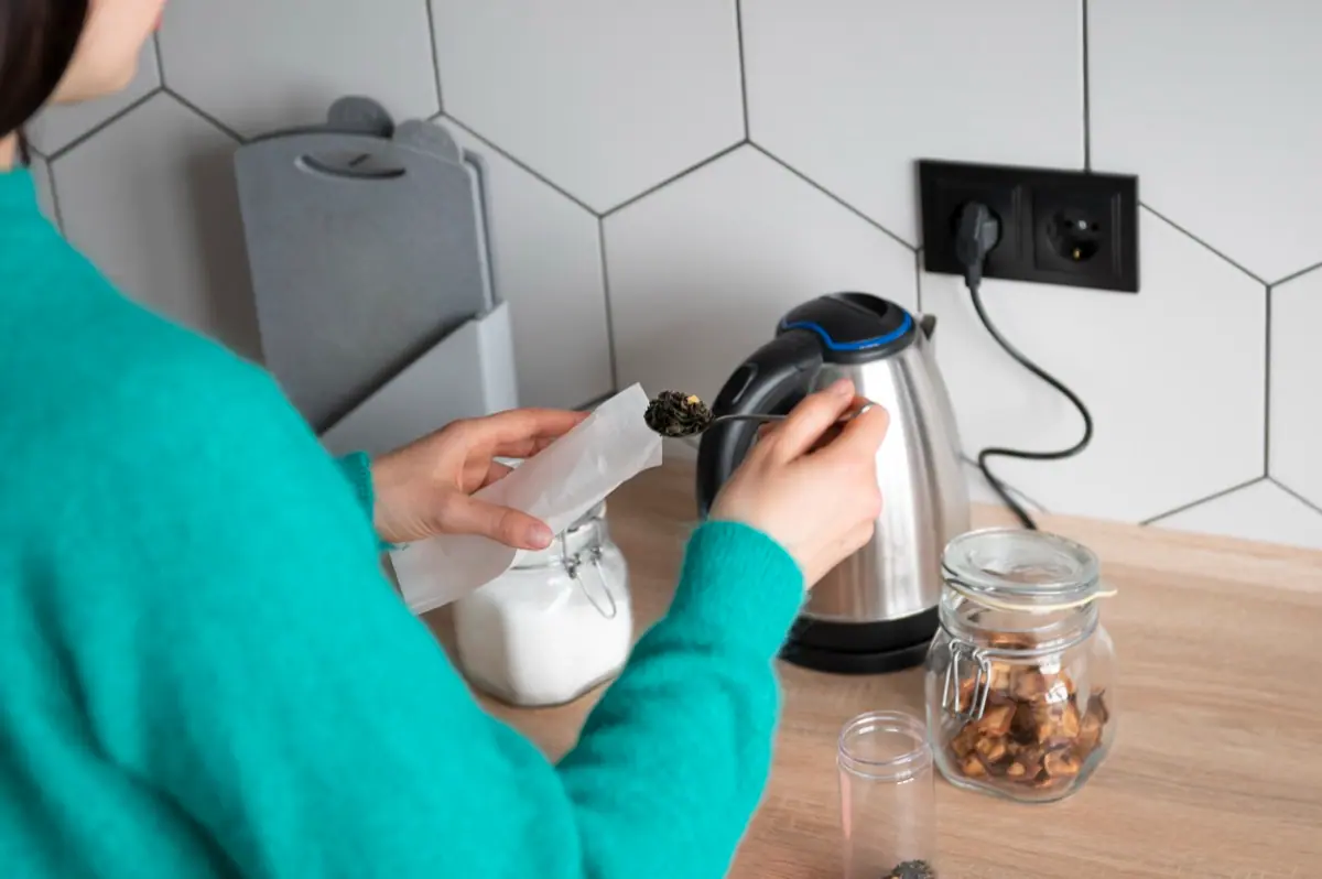 Kobieta i czajnik elektryczny do gniazdka w kuchni